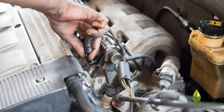 A mechanic in a Toyota dealership service bay performs an oil change on a lifted Toyota vehicle.